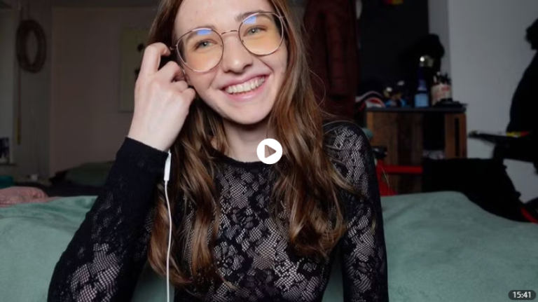 Emmi Hill lächelt mit Brille und schwarzem Spitzenoberteil gemütlich in die Kamera und versprüht süße GenZ- & Cozy-Vibes.